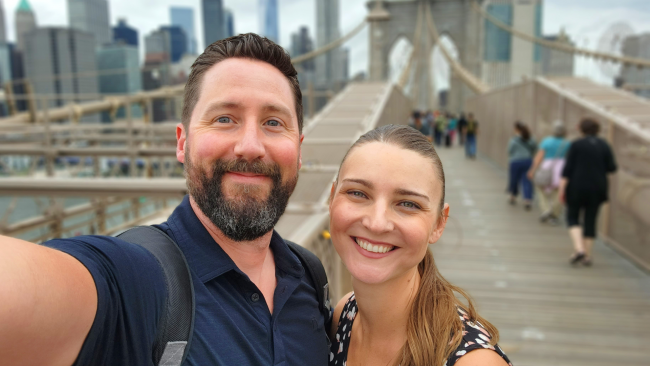 Chris and Karen posing and smiling at the end of the Brooklyn bridge.