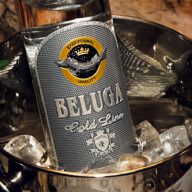 A fresh bottle of Beluga Gold Line vodka "exceptional quality" in a stainless steel ice bucket filled with cubed ice.