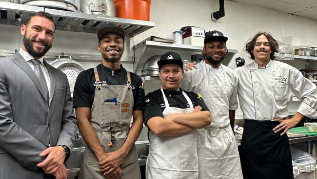 Chef Dom and his teammates from the Arboretum standing in the kitchen smiling and posing together