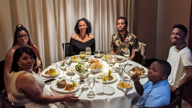 Chef Dom and his family at Truluck's in Dc at a large round table draped in linen with a full meal set on the table