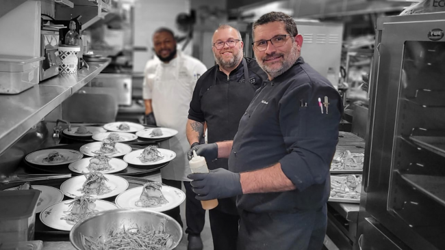 Chef Joe Mora and Odel Arencibia on the kitchen line plating up entrees for a special event.