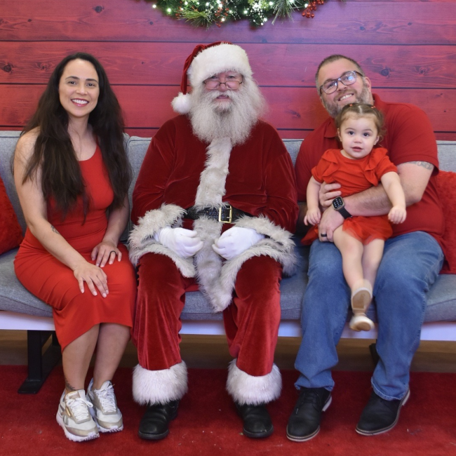 Chef Joe Mora with his wife and daughter seated with Santa Clause and all the family wearing red