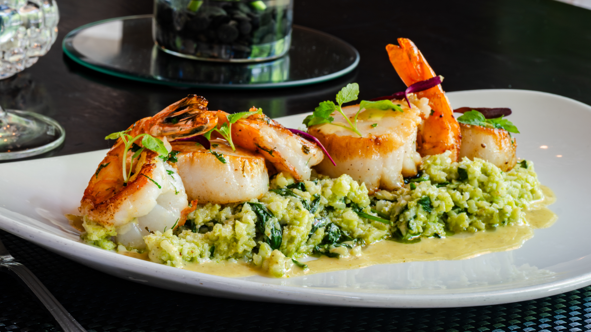 scallop and shrimp saute over florentine cauliflower rice, lemon vinaigrette on a white china plate