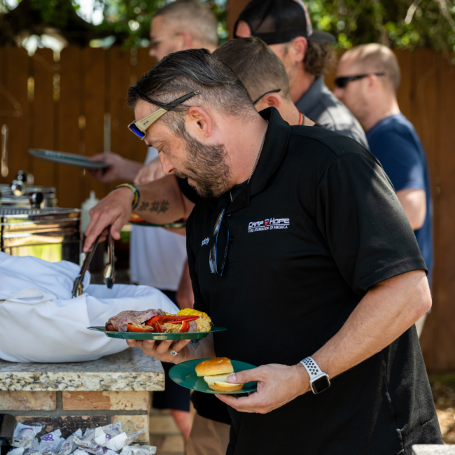 Guests of Camp Hope going through the buffet line to get plates of lobster boil and prime rib slider sandwiches