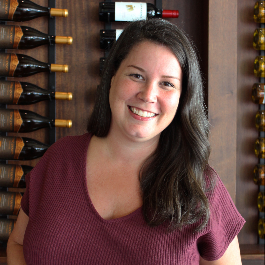 headshot of Monica Leibowitz of Truluck's Dallas in a marroon blouse in front of a wooden wall with wine bottles mounted