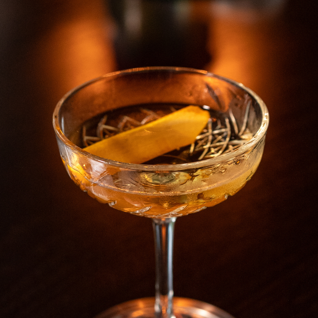 Slightly overhead shot of the Tesoro tequila martini in a crystal stemmed glass with a lemon twist garnish