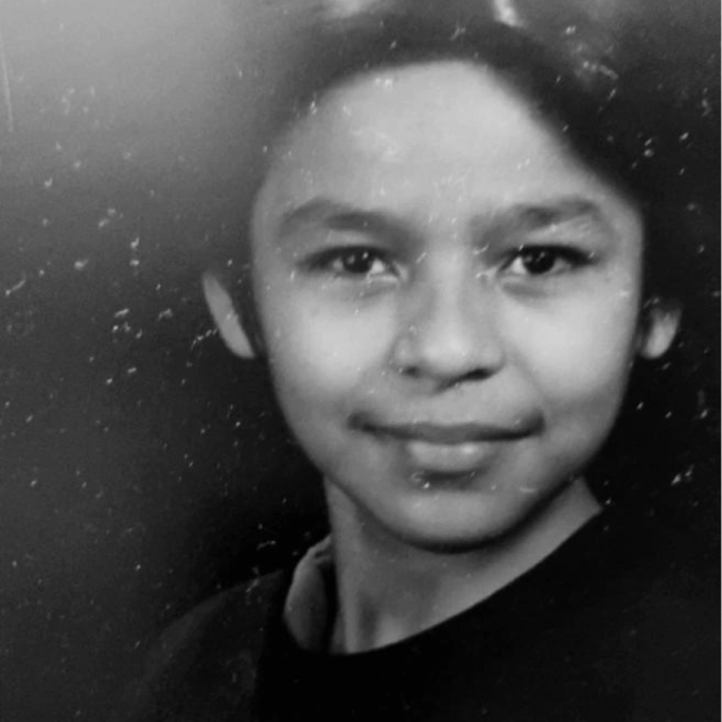 Rey Resendez as a young boy smiling without teeth and wearing a black shirt