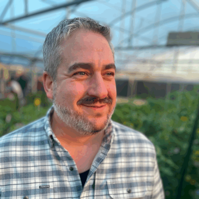 photo of Ryan Studt Dallas general manager in a plaid shirt with a mustache and beard standing in an indoor garden
