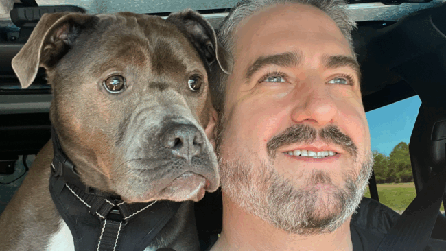 Ryan Studt close up shot of him and his dog looking out the car window