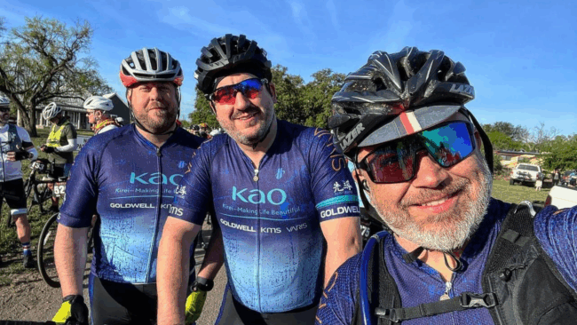 Ryan Studt with 2 cycling buddies wearing bike helmets and cycling shirts that say "KAO" on them