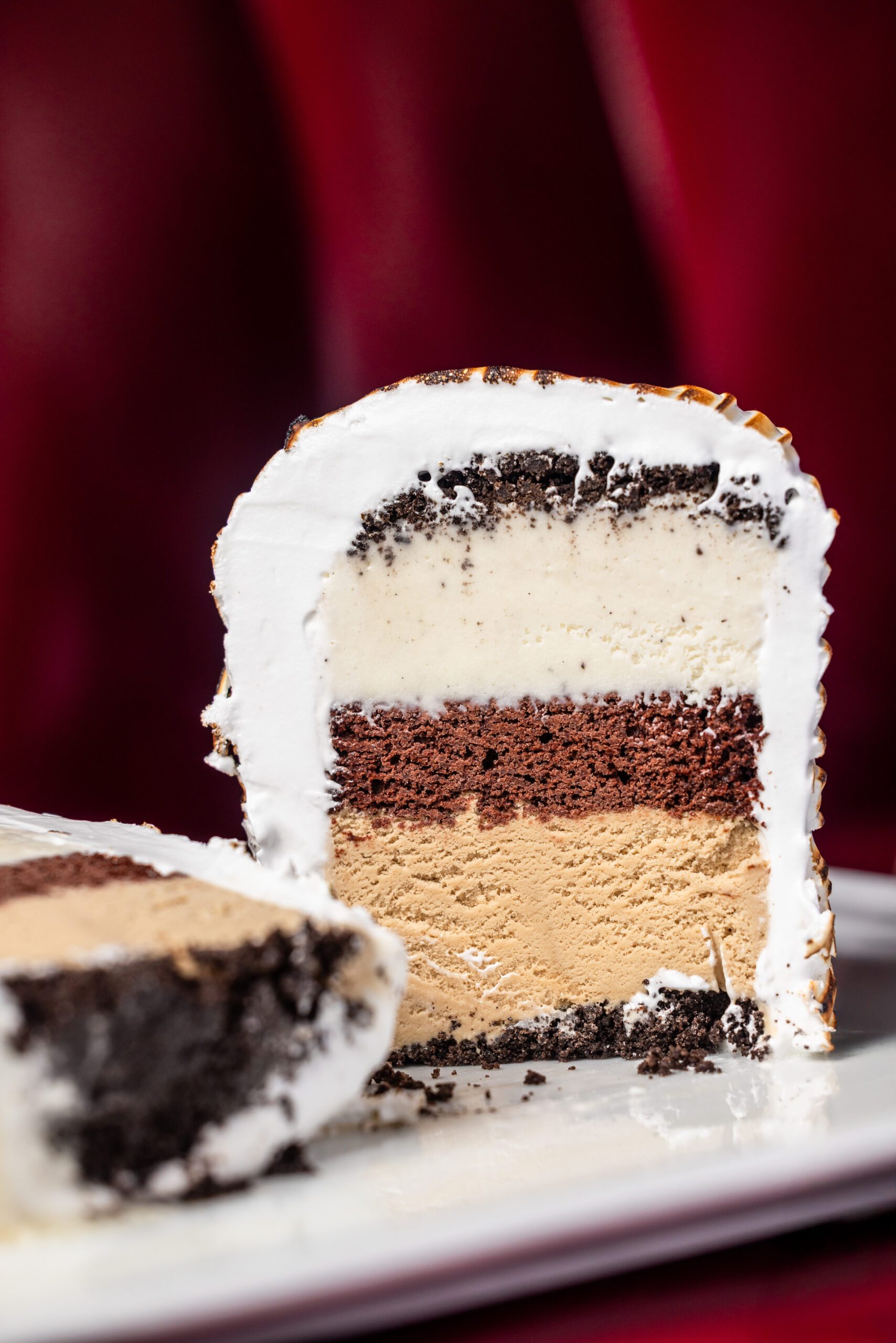 the inside of a Baked Alaska dessert showing layers of chocolate cake between vanilla bean and coffee ice cream with a meringue icing