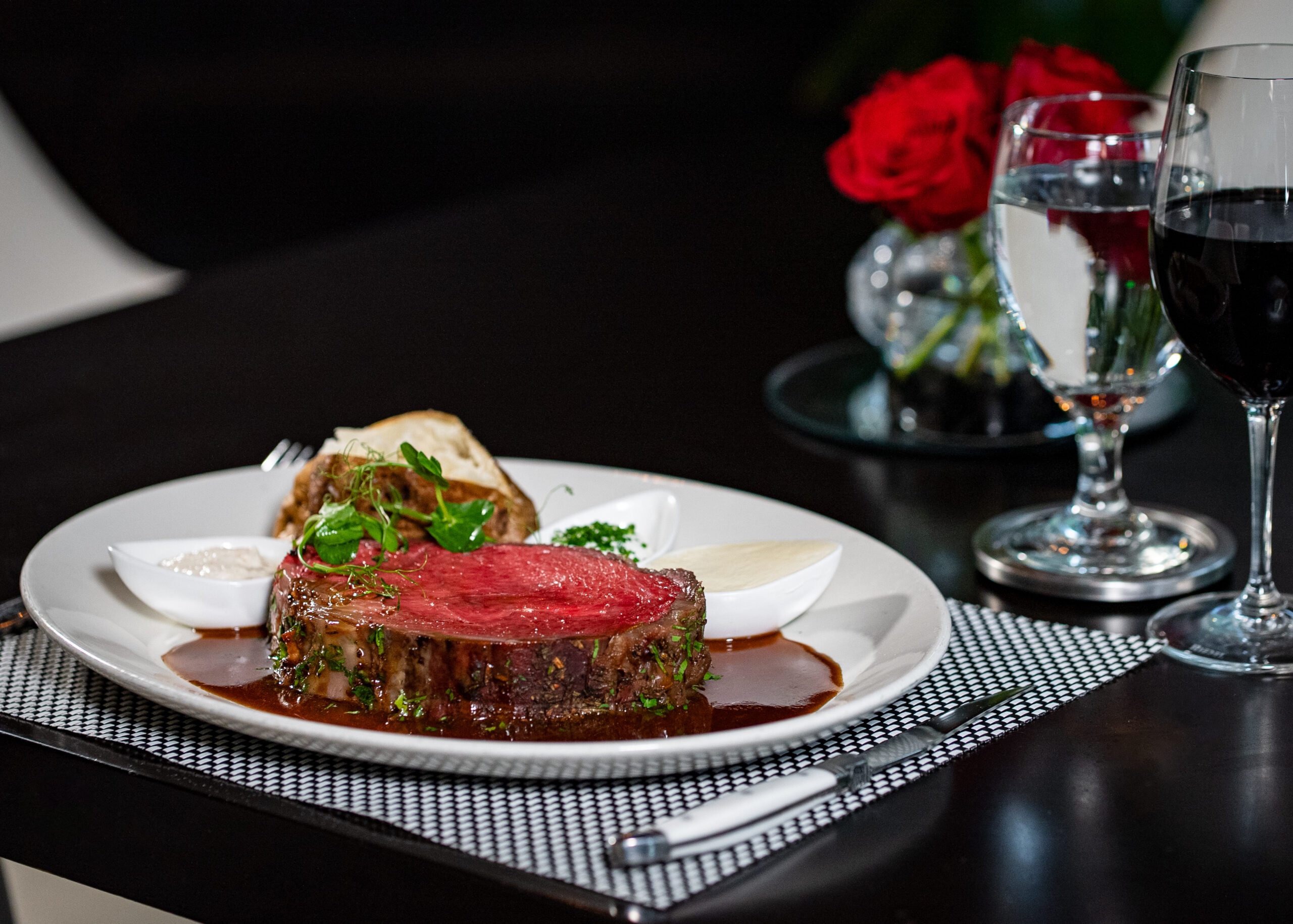 a large cut of rare prime rib steak with au jus and a trio of sauces