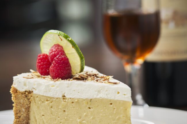 key lime pie topped with slivered almonds, fresh raspberries and a key lime wheel