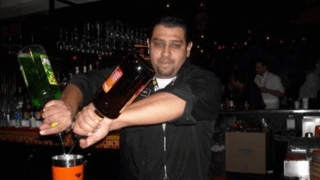 Blake Goldie bartending earlier in his career, pouring cocktails behind a busy bar during his hospitality beginnings