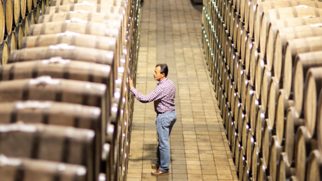 A tequila producer inspecting oak barrels as they age in the El Tesoro traditional barrel warehouse.