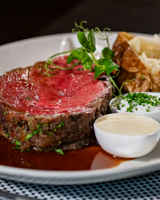 Truluck’s Prime Rib served with au jus, horseradish cream, sour cream with chives, mashed potatoes, and a baked potato.