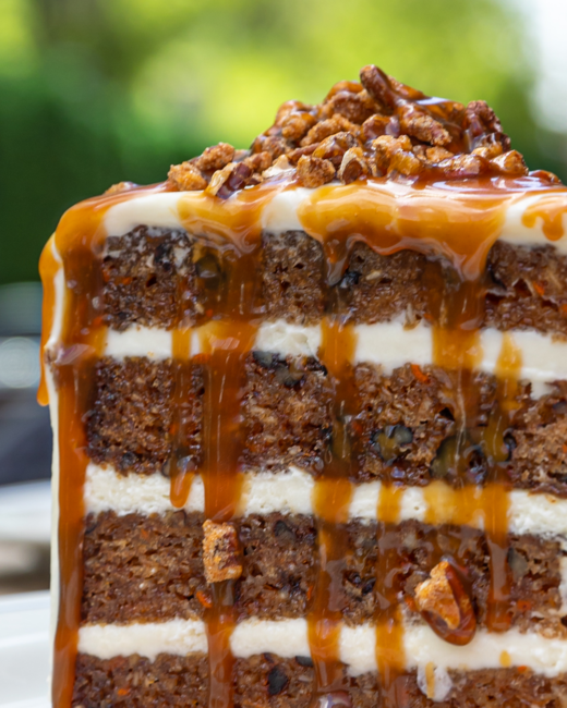 Close-up of Truluck’s World Class Carrot Cake layered with cream cheese frosting, caramel sauce, and candied pecans.