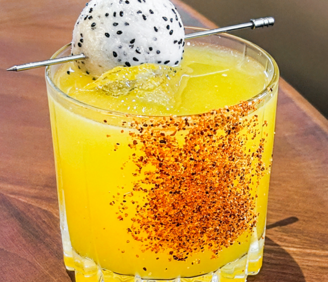A Truluck's signature cocktail with mango, Tajín spice rim, and dragon fruit garnish — part of the seasonal cocktail menu available during World Cup match weeks