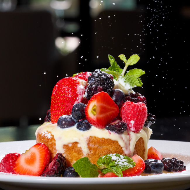 Seasonal berry pound cake topped with cream, fresh strawberries, raspberries, blueberries, blackberries, mint, and a dusting of powdered sugar.