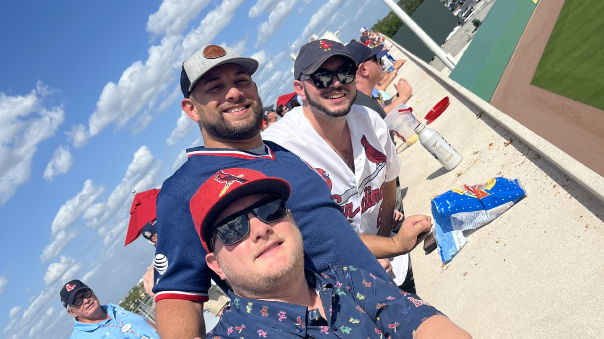 Johnny Griesedieck of Truluck’s Naples taking a selfie with friends at an outdoor baseball game on a sunny day.
