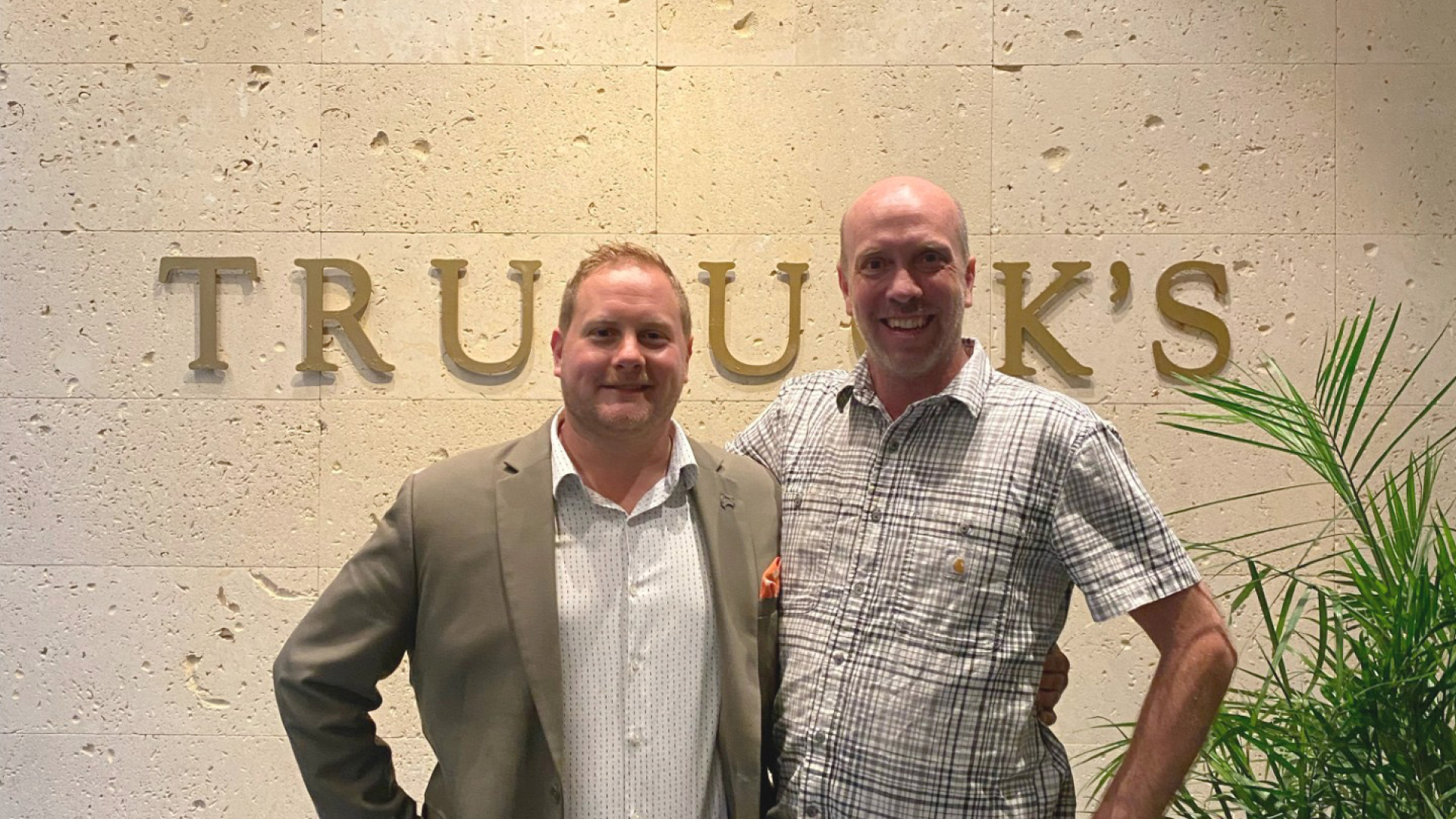 Johnny Griesedieck, General Manager of Truluck’s Naples, pictured with a guest in front of the Truluck’s sign inside the restaurant.