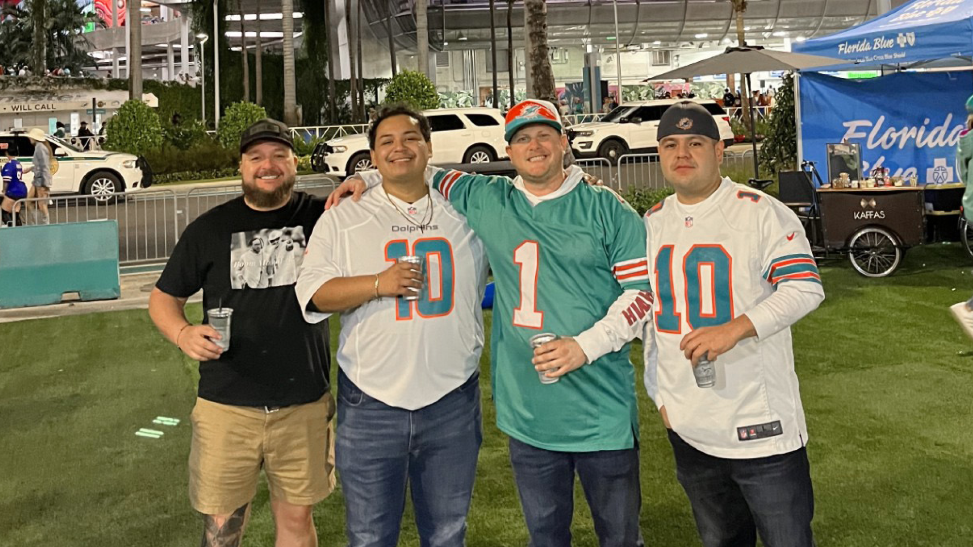 Johnny Griesedieck of Truluck’s Naples posing with friends in Miami Dolphins jerseys outside a stadium.