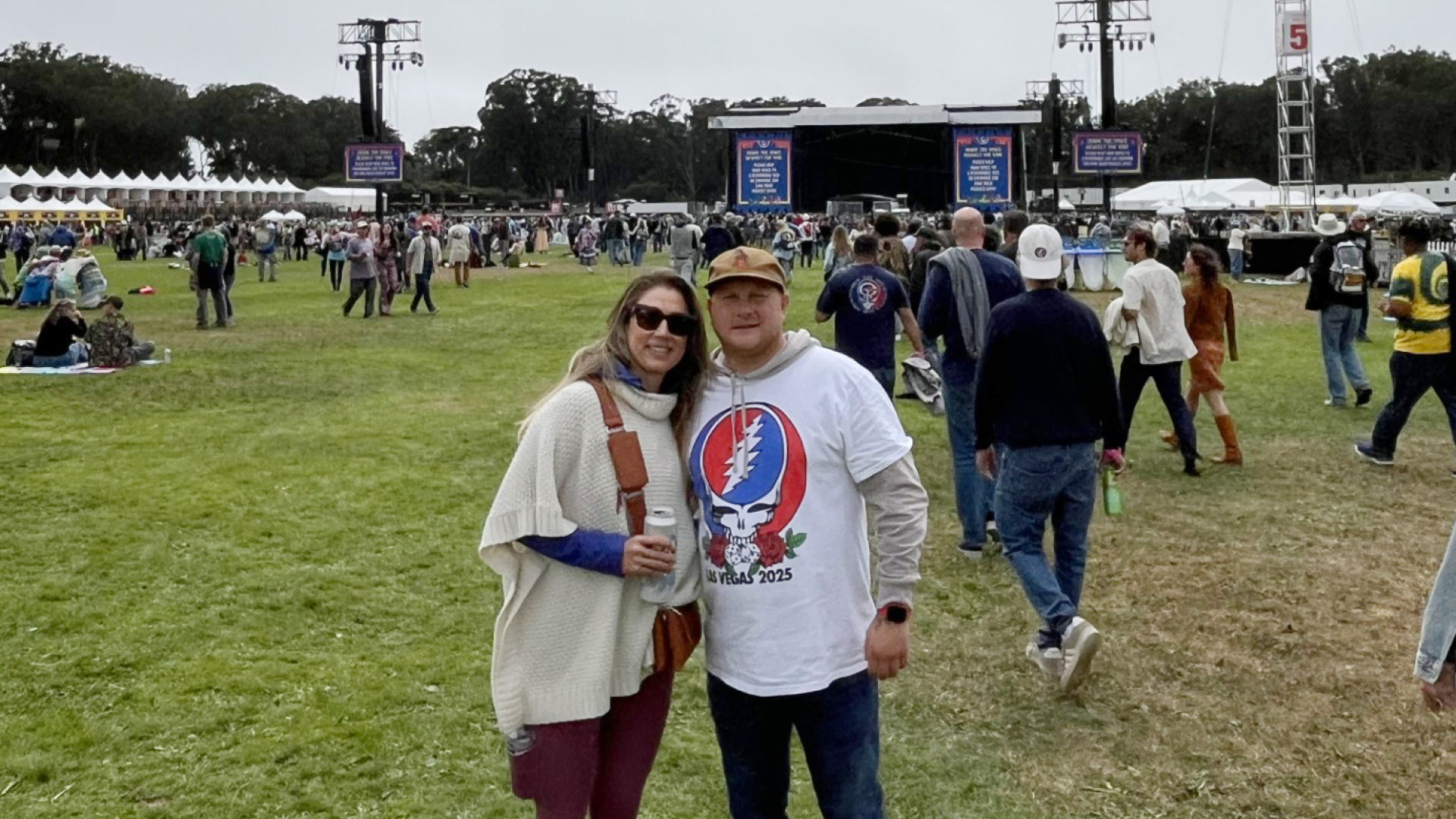 Johnny Griesedieck of Truluck’s Naples posing with a companion at an outdoor music festival with a stage and crowd in the background.