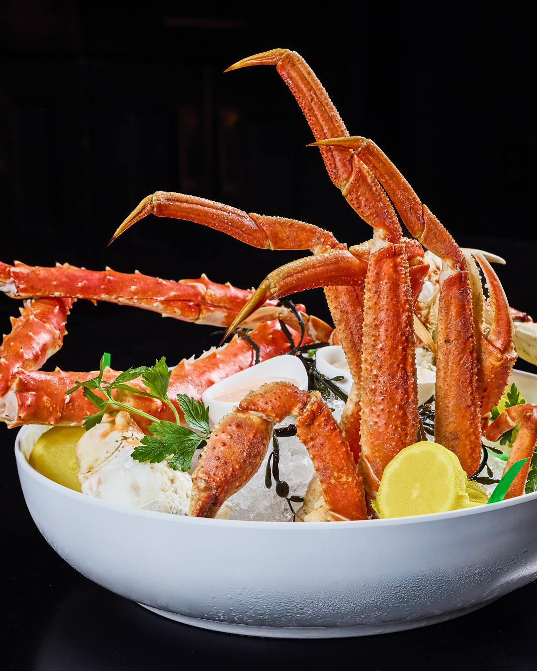 Alaskan king crab legs served chilled over crushed ice with lemon, parsley, and dipping sauce.