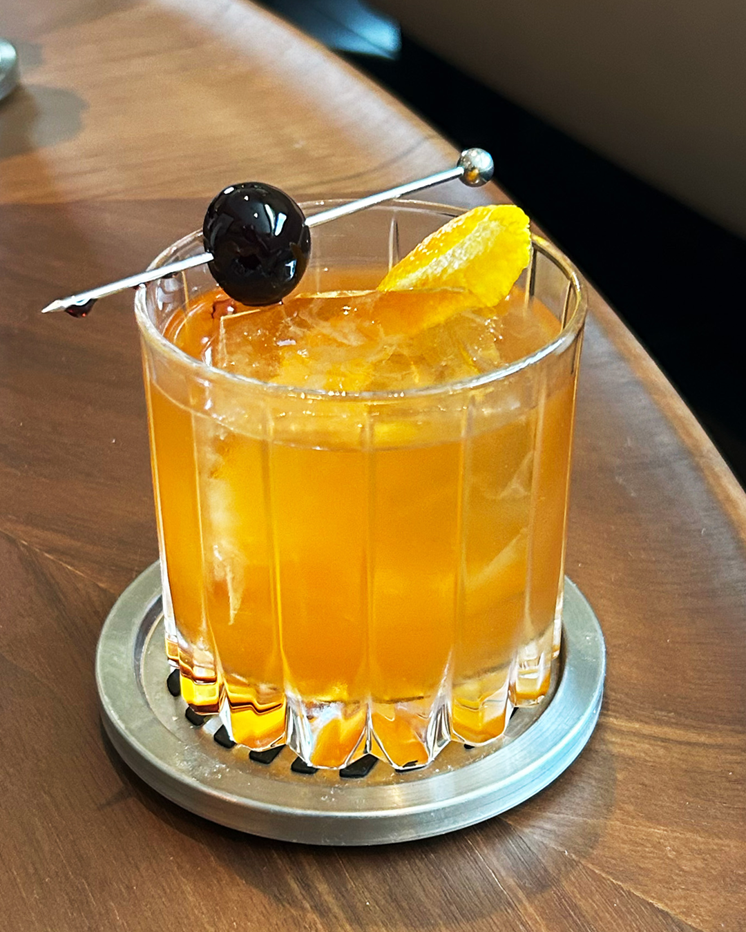 Toasted Pecan Old Fashioned cocktail served over ice with an orange peel and cherry garnish.